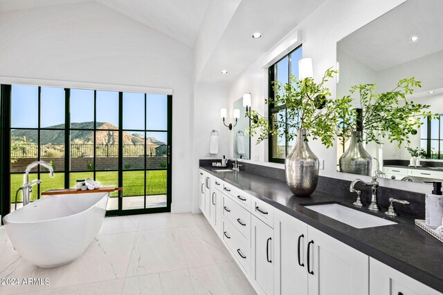 bathroom featuring vanity, vaulted ceiling, and a bath