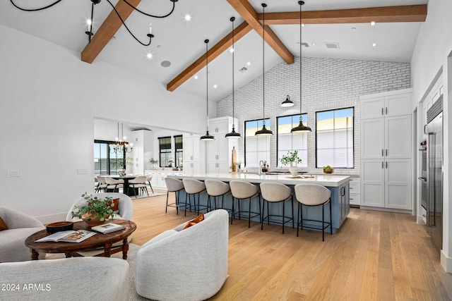 living room with a chandelier, sink, beam ceiling, high vaulted ceiling, and light hardwood / wood-style flooring