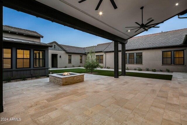 back house at dusk with a lawn and a patio area