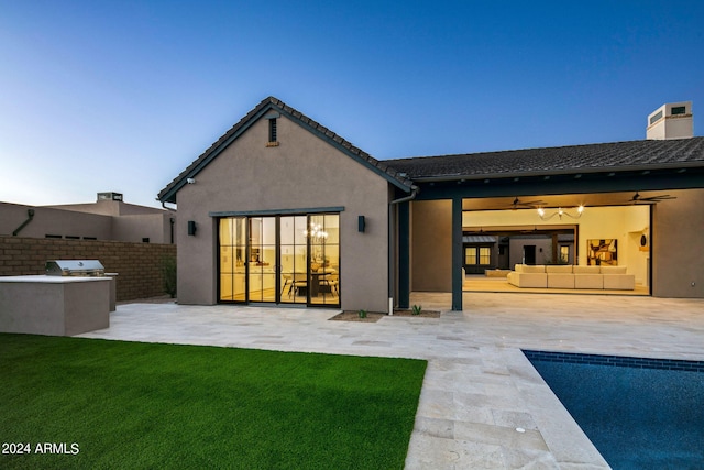 rear view of house with a yard, ceiling fan, a fenced in pool, and a patio area