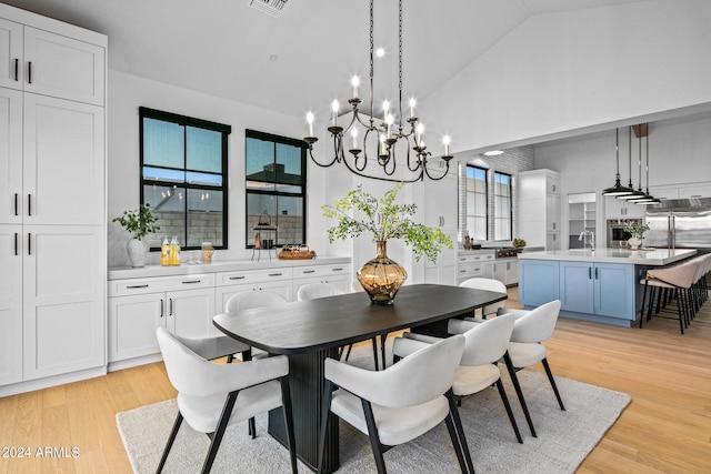 dining area featuring high vaulted ceiling, sink, light hardwood / wood-style flooring, and a notable chandelier