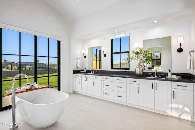 bathroom featuring a tub to relax in, vanity, high vaulted ceiling, and plenty of natural light