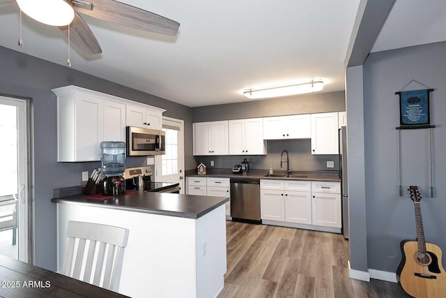 kitchen featuring sink, white cabinetry, light wood-type flooring, kitchen peninsula, and stainless steel appliances