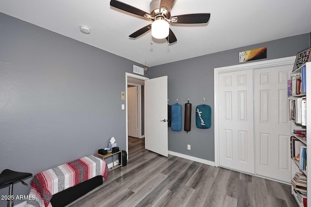 bedroom with hardwood / wood-style flooring, ceiling fan, and a closet