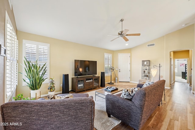 living room with light wood finished floors, visible vents, arched walkways, a ceiling fan, and lofted ceiling