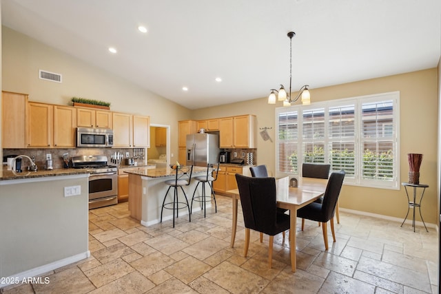 kitchen featuring light brown cabinets, stainless steel appliances, visible vents, baseboards, and stone tile flooring