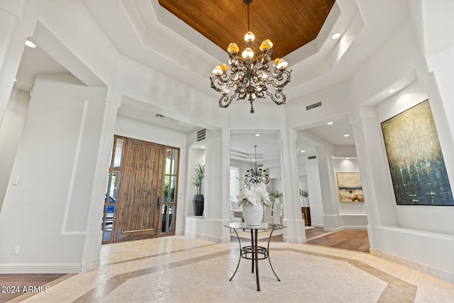 foyer entrance with a tray ceiling, wood ceiling, hardwood / wood-style flooring, and a notable chandelier