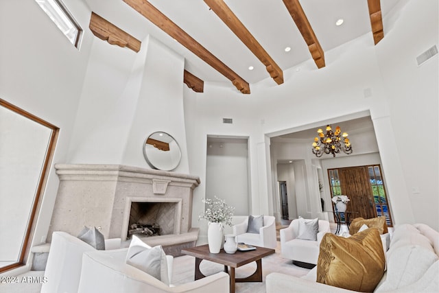 living room featuring a towering ceiling, a premium fireplace, an inviting chandelier, and beam ceiling