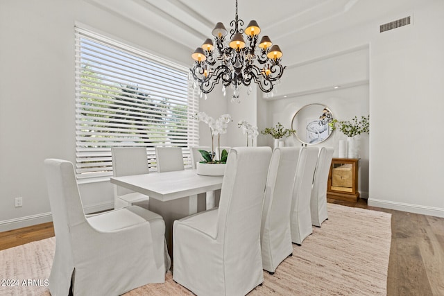 dining area with light hardwood / wood-style flooring and an inviting chandelier