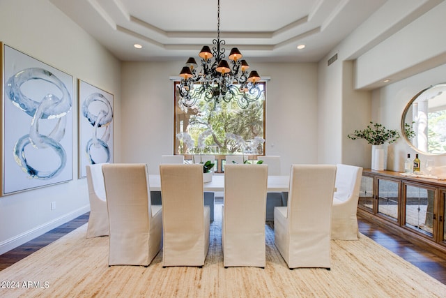 dining space featuring hardwood / wood-style floors, a tray ceiling, and an inviting chandelier