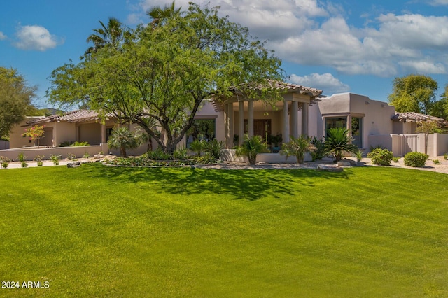 view of front facade with a tiled roof, a front lawn, fence, and stucco siding