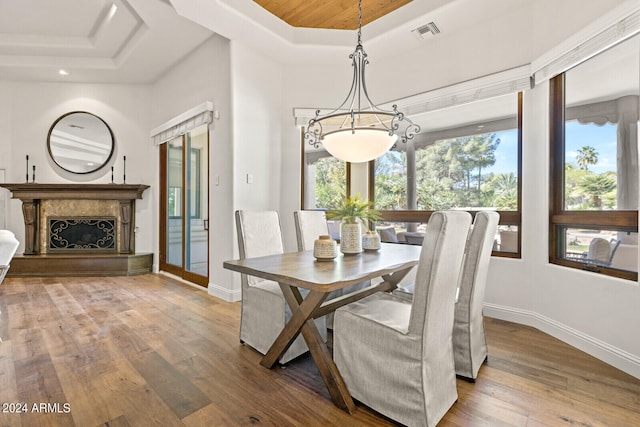 dining area featuring hardwood / wood-style flooring, a tray ceiling, and a fireplace