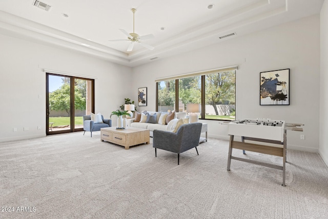 living room with ceiling fan, light carpet, and a tray ceiling