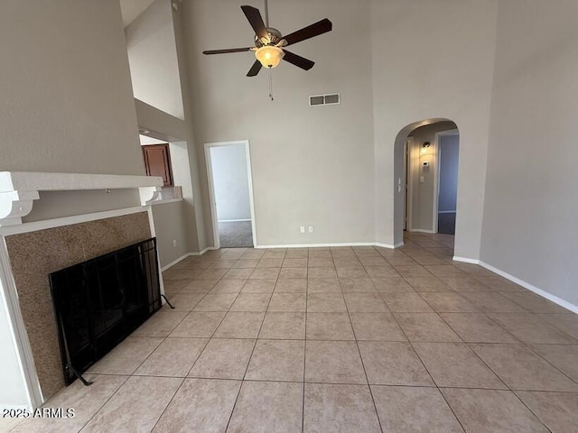 unfurnished living room featuring light tile patterned flooring, ceiling fan, and a high ceiling