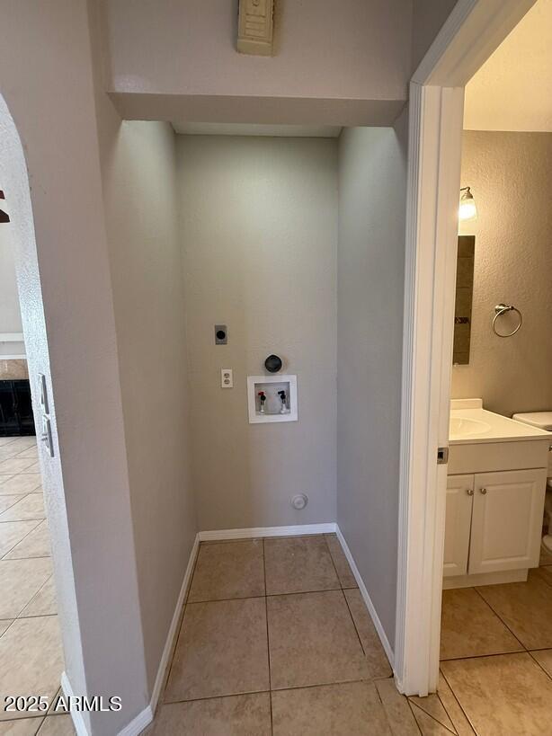 washroom featuring light tile patterned flooring, electric dryer hookup, sink, and washer hookup