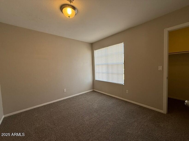 unfurnished bedroom featuring dark carpet, a spacious closet, and a closet