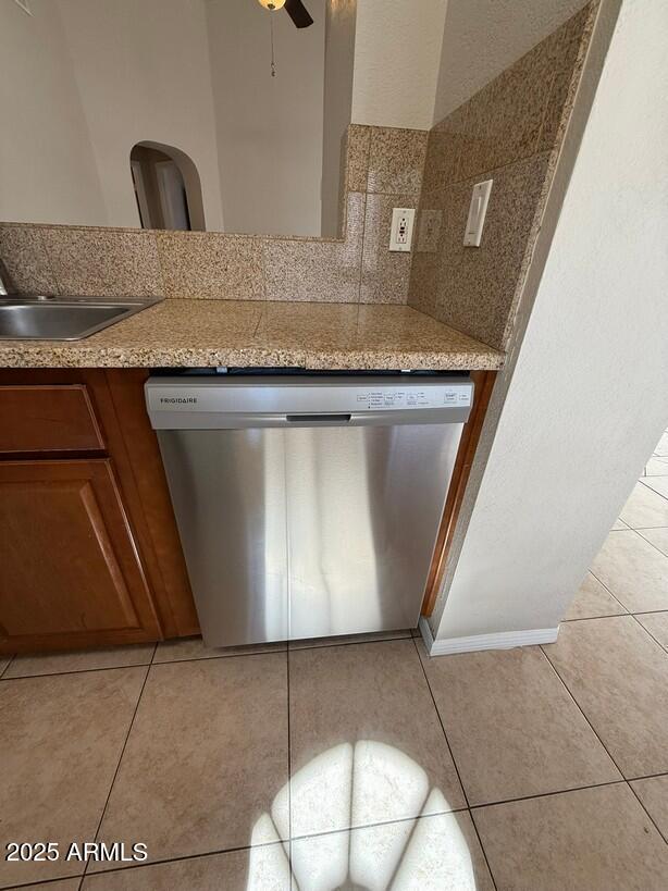 kitchen featuring sink, ceiling fan, tasteful backsplash, light tile patterned flooring, and stainless steel dishwasher