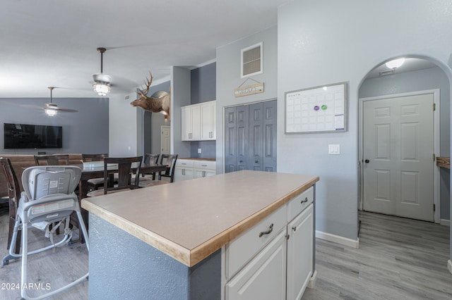 kitchen featuring light wood-type flooring, ceiling fan, pendant lighting, white cabinets, and a kitchen island