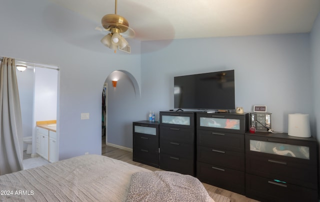 bedroom featuring connected bathroom, ceiling fan, light hardwood / wood-style flooring, and vaulted ceiling