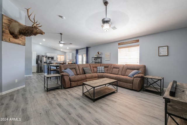 living room with ceiling fan, lofted ceiling, and light hardwood / wood-style flooring