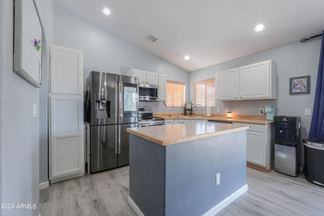 kitchen featuring a center island, vaulted ceiling, light hardwood / wood-style floors, white cabinetry, and stainless steel appliances