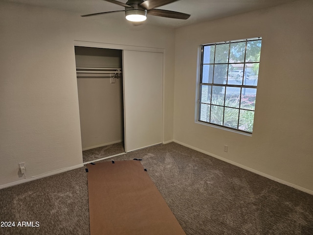 unfurnished bedroom featuring ceiling fan, a closet, and dark colored carpet