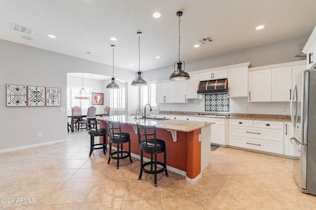 kitchen with pendant lighting, white cabinets, a center island with sink, and appliances with stainless steel finishes