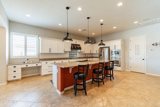 kitchen featuring white cabinets, a center island with sink, stainless steel appliances, a kitchen breakfast bar, and light stone countertops