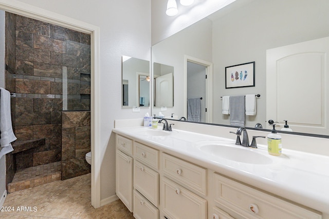 bathroom with a tile shower, vanity, toilet, and tile patterned floors