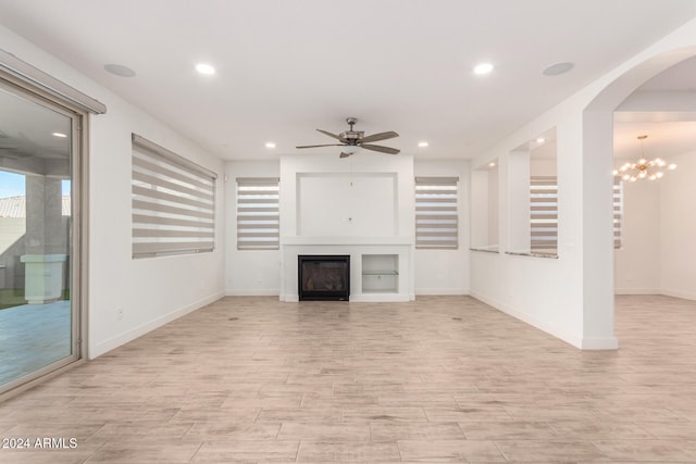 unfurnished living room with ceiling fan with notable chandelier