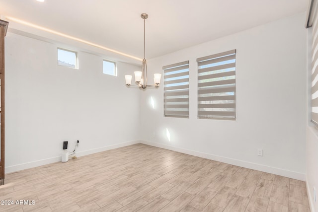 spare room featuring light hardwood / wood-style flooring and a notable chandelier