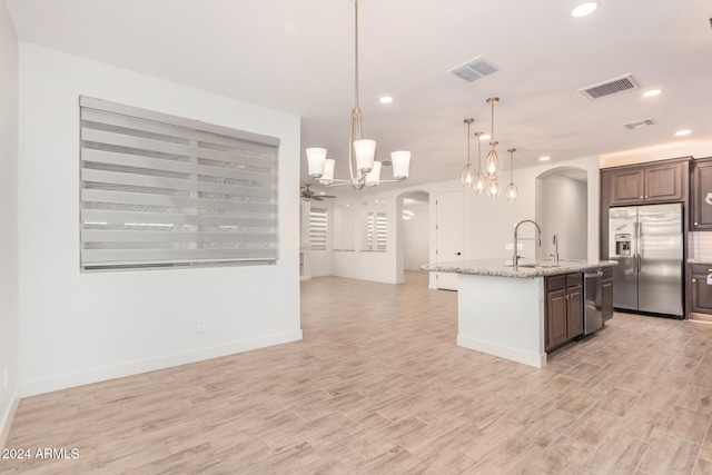 kitchen with stainless steel appliances, hanging light fixtures, sink, an island with sink, and dark brown cabinets