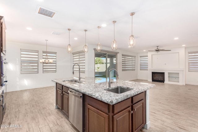 kitchen with sink, light wood-type flooring, a kitchen island with sink, pendant lighting, and dishwasher