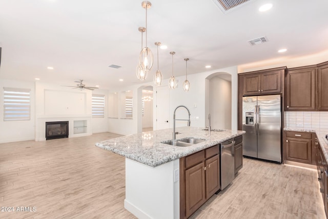 kitchen featuring light wood-type flooring, appliances with stainless steel finishes, sink, and an island with sink