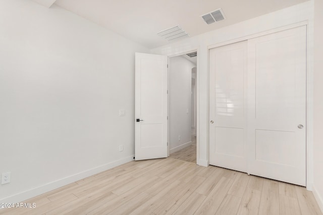 unfurnished bedroom with a closet and light hardwood / wood-style floors