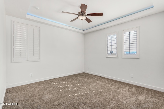 carpeted spare room featuring ceiling fan and a raised ceiling