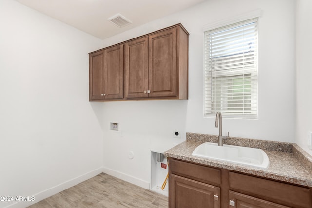 laundry area with hookup for an electric dryer, cabinets, sink, washer hookup, and light wood-type flooring