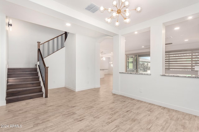 unfurnished living room featuring light hardwood / wood-style floors and a notable chandelier