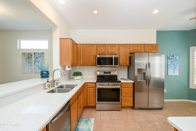 kitchen featuring stainless steel appliances, light stone countertops, sink, and light tile patterned flooring