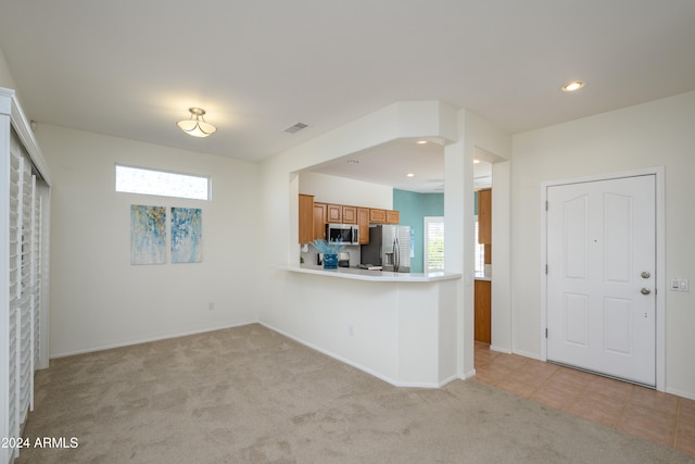 kitchen featuring light carpet, kitchen peninsula, and stainless steel appliances