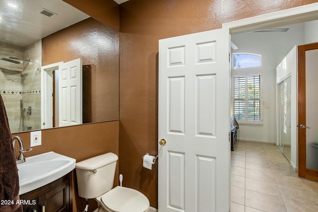 bathroom featuring a tile shower, tile patterned flooring, vanity, and toilet