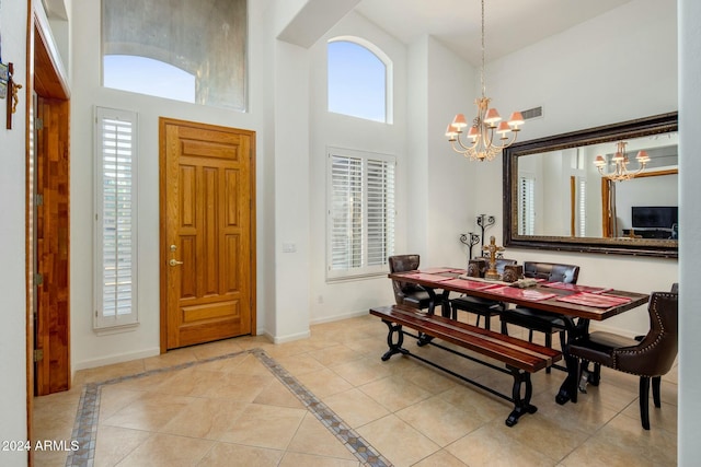 dining room featuring light tile patterned floors, a towering ceiling, and a notable chandelier