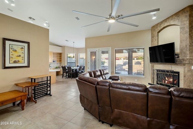 tiled living room with a wealth of natural light, a fireplace, ceiling fan, and vaulted ceiling