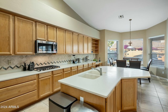 kitchen featuring tasteful backsplash, stainless steel appliances, a kitchen island with sink, and sink