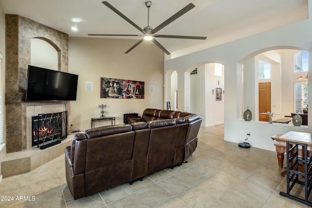 living room featuring a tile fireplace, ceiling fan, light tile patterned flooring, and lofted ceiling