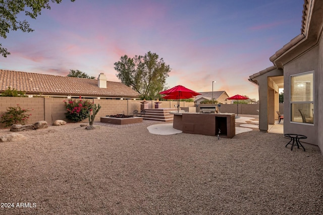 yard at dusk featuring a patio and area for grilling