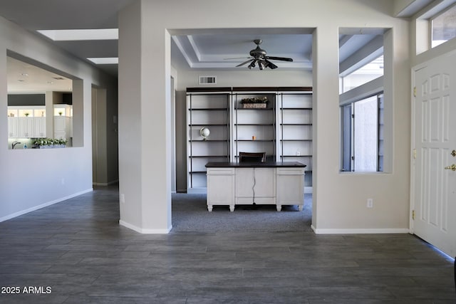 unfurnished office with a tray ceiling, dark wood-type flooring, and a wealth of natural light