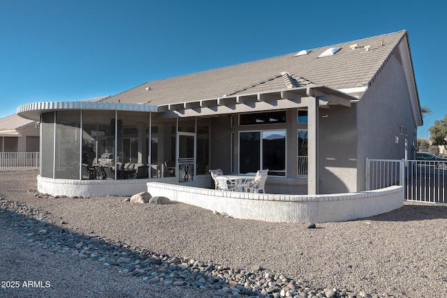 rear view of property with a sunroom and a patio area