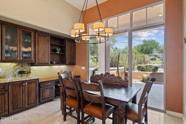 tiled dining room with high vaulted ceiling and an inviting chandelier