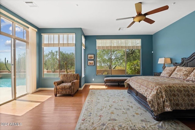 bedroom featuring ceiling fan, access to outside, multiple windows, and hardwood / wood-style floors